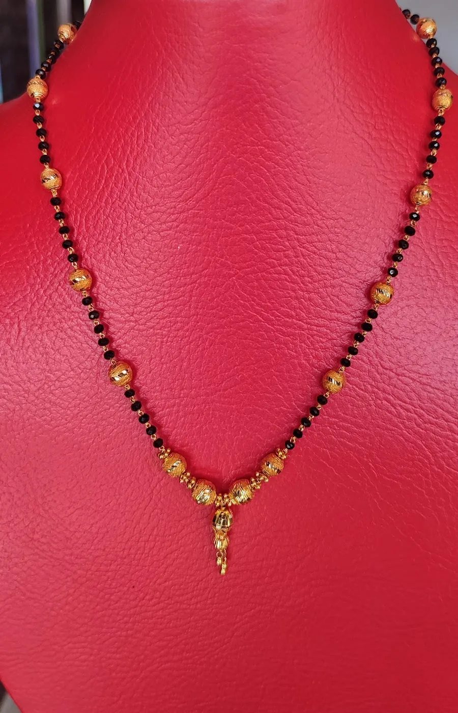 Black bead and gold mangalsutra necklace on a red bust